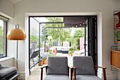 Zwei graue Sessel im Retrostil mit Blick auf die Gartenterrasse in einem modernisierten Haus in Preston, Lancashire, England UK