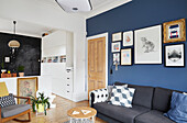 Framed artwork on blue feature wall above sofa in home office of modernised Preston home  Lancashire  England  UK