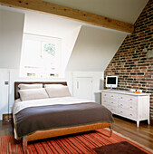 Converted attic double bedroom with exposed brick wall and dormer window 