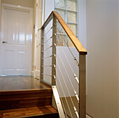 Walnut staircase with modern steel bannister rail leading to upstairs landing