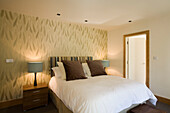 Neutrally decorated bedroom with wallpaper and bedside lamps