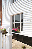 Weiß getäfelte Außenfassade des Cottage in Brighlingsea und Lattenzaun mit Blumenkästen