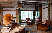 Gramophone and books on table with matching brown leather chairs in watermill conversion 