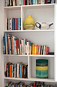 Bücher und Keramikvasen in einem Bücherregal in Essex, UK