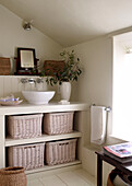 Built in unit with countertop wash basin and storage baskets in attic bathroom painted in neutral tones