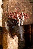 Stone fireplace detail with wall mounted carved wood deer head and red berry christmas decorations
