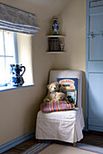 Teddy bears on upholstered chair in corner of cottage bedroom