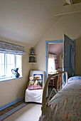 Soft toys on chair in bedroom with metal footboard and sunlit window