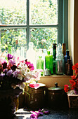 Uncurtained window with bottle collection and view to garden 