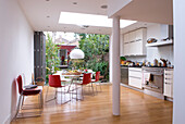 Red chairs at table in modern London kitchen extension