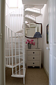 Spiral staircase with a chest of drawers and mirror 