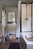 Badezimmer in neutralen Tönen mit hoher Decke und schwarz-weißen Wandfliesen und großem Duschkopf über der Badewanne