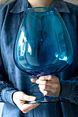 Frau hält große blaue Glasvase