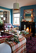 Lit fire and fairy lights with wooden coffee table in country home at Christmas