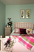 Pink checked blanket on bed with mistletoe and mirrored floral artwork