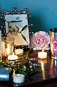 Lit tea lights and jeweled picture frame on wooden dressing table