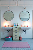 Circular mirrors hang above double wash basins in Odense bathroom