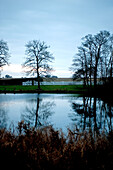 Winterbäume, die sich im stillen Wasser des Odense-Sees spiegeln Dänemark