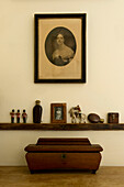 Holzschatulle unter Regal mit Ornamenten und Familienporträt