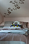 Variety of cushions on double bed under ceiling with floral wall decoration in London home UK