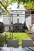 Begrünter Außenbereich eines weißen Londoner Stadthauses mit Wintergartenanbau England UK