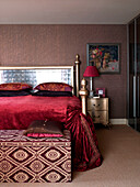 Bettbezug aus rotem Samt auf goldenem Bett mit gemustertem Deckenkasten im Schlafzimmer einer Londoner Wohnung England UK