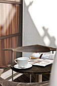 Tasse und Untertasse mit aufgeschlagener Zeitschrift auf dem Tisch einer Balkonaußenwohnung in London England UK