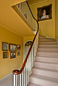 Artwork in carpeted yellow staircase of rural Suffolk home England UK