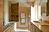 Sonnendurchflutetes Badezimmer mit Doppelwaschbecken und eingelassenen Glasregalen in einem Haus im ländlichen Suffolk England UK