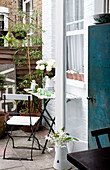 View through back door to folding chair and table in yard of London home, UK