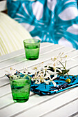 Sprig of flowering blossom on napkin at table with green glassware, London, UK