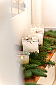 Lit candles and pine needles on shelf in Forest Row family home, Sussex, England, UK