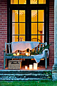 Fur throw on bench seat with lit candles, Forest Row family home, Sussex, England, UK