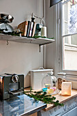 Recipe books and scales on shelf above kitchen counter with stainless steel coffee machine in Paris apartment, France