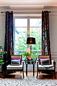 Pair of wooden armchairs at french doors in Paris apartment, France