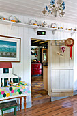 Dolls house in hallway with shelf above door and view into kitchen of Essex home, England, UK