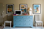 Turquoise sideboard with vintage prints and a pair of cane chairs in Buckinghamshire home, England, UK