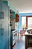 Crockery hanging above range oven in turquoise kitchen of Bovey Tracey family home, Devon, England, UK