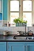 Herbs on kitchen windowsill with double sink in Bovey Tracey family home, Devon, England, UK