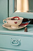 Vintage-Tasse mit Untertasse auf einem bemalten Schminktisch im Schlafzimmer eines Hauses der Familie Bovey Tracey, Devon, England, UK