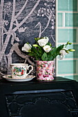 Cut flowers with vintage teacup in bathroom of Bovey Tracey family home, Devon, England, UK