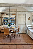 Wooden circular table with dresser in tiled kitchen of Suffolk farmhouse, England, UK