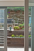Blick durch die Tür zur Terrasse mit Möbeln und Topfpflanzen in Wadebridge, Cornwall, England, UK