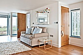 Zweisitzer-Sofa unter verschnörkeltem weißen Spiegel im Wohnzimmer eines Hauses in Wadebridge, Cornwall, England, UK
