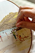 Woman working on tapestry of beach scene in Cornwall, England, UK