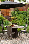 Table and chairs with parasol on patio of Middlesex home, London, England, UK