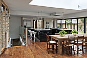 Wooden dining table and chairs in open plan dining room kitchen of London home, England, UK