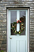 Weihnachtsgirlande an der Eingangstür eines Bauernhauses aus Stein, Cornwall, England, UK