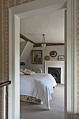 View through doorway of embroidered cushions on bed in Suffolk country house, England, UK