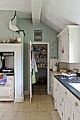 Fahnensteinboden mit Vogelornament in hellgrüner Küche eines modernen Hauses in Suffolk/Essex, England, UK